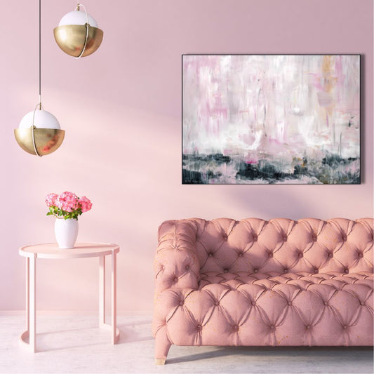 Pink living room with a tufted sofa, side table with flowers, and abstract art on the wall.