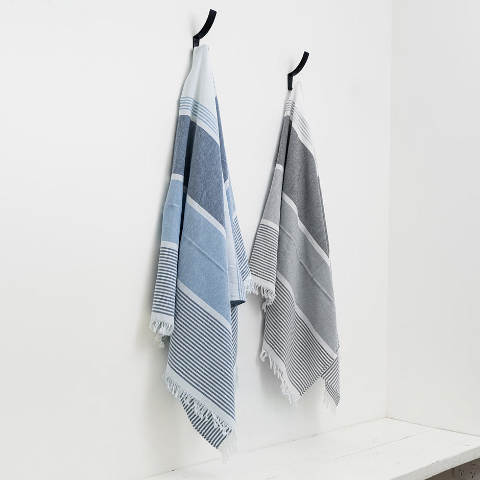 Two striped towels hanging on hooks against a white wall.