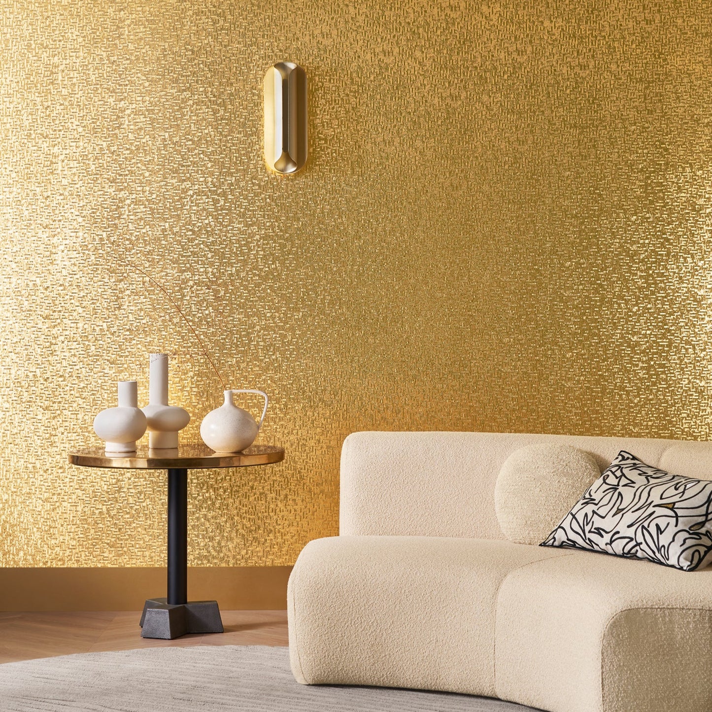 Modern living room with gold textured wall, beige sofa, and decorative table.