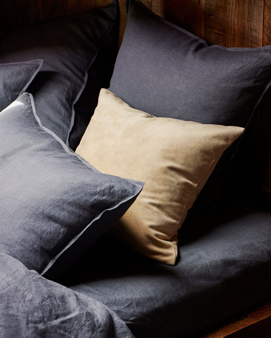 Gray and beige pillows on a sofa with a wooden headboard.
