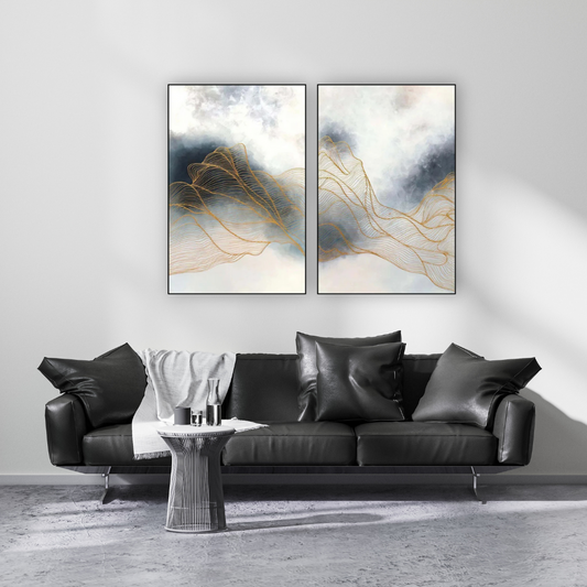 Abstract pair of paintings in moody skies with gold lattice lines hung above a black modernleather sofa