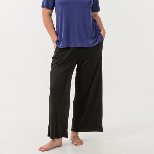 Woman wearing a blue top and black silk
pants on a white background