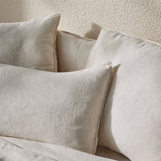 Beige pillows and bedding on a textured beige wall background