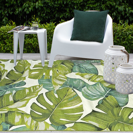 Tropical leaf patterned rug with a white chair and green pillow in a garden setting.