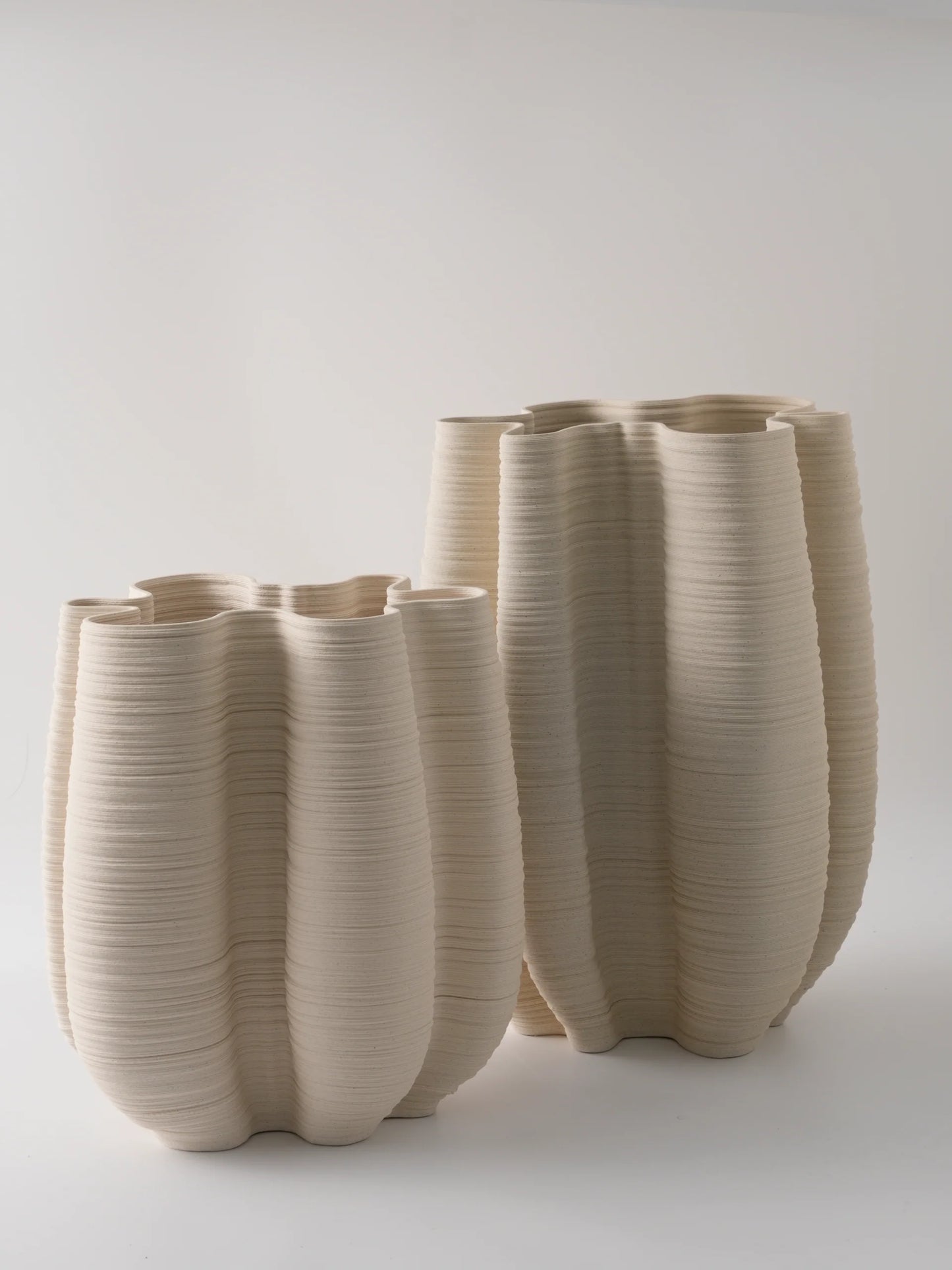 Set of three beige ceramic vases with textured surface on a white background
