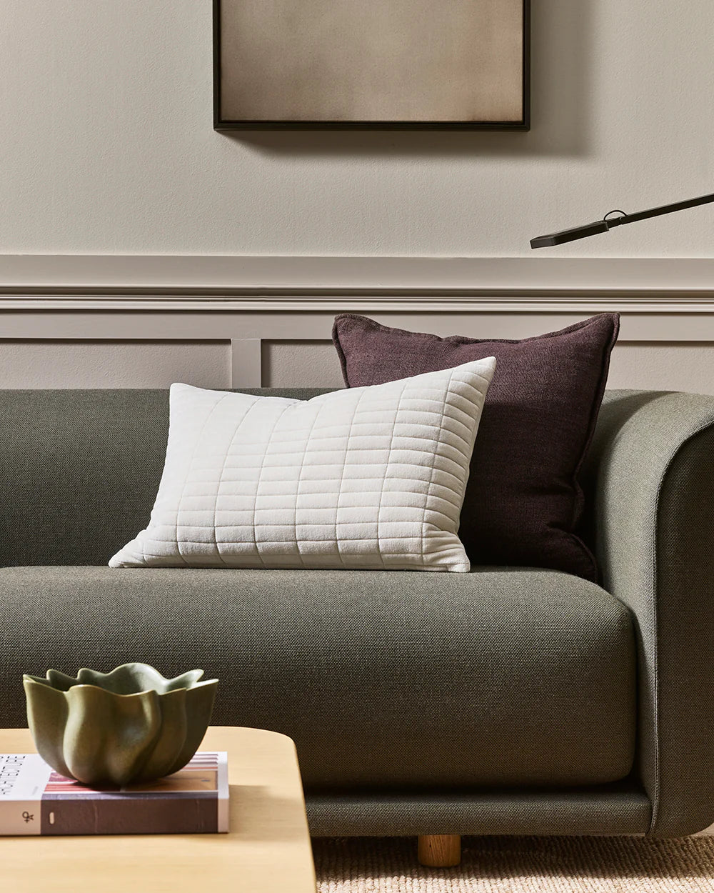 Gray sofa with white and brown quilted pillows in a living room setting.