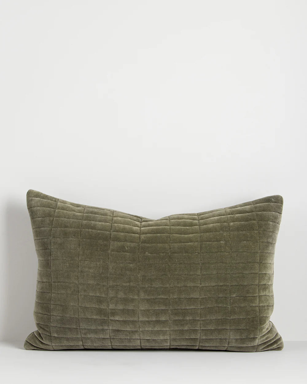 Quilted olive green pillow on a white background