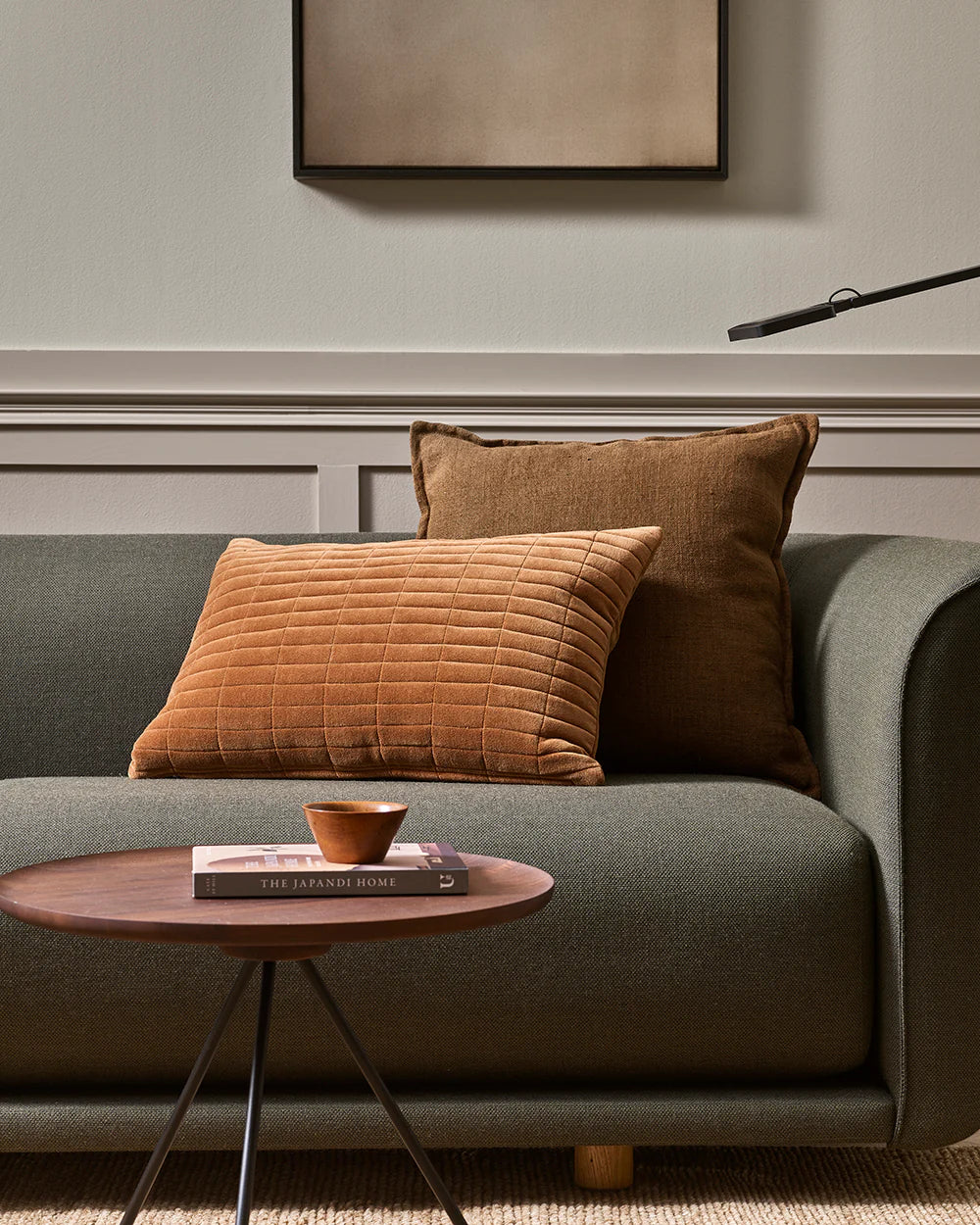 Gray sofa with brown and orange cushions and a small wooden table in a living room setting.