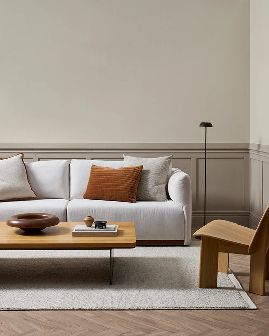 Modern living room with a white sofa, wooden coffee table, and chair.