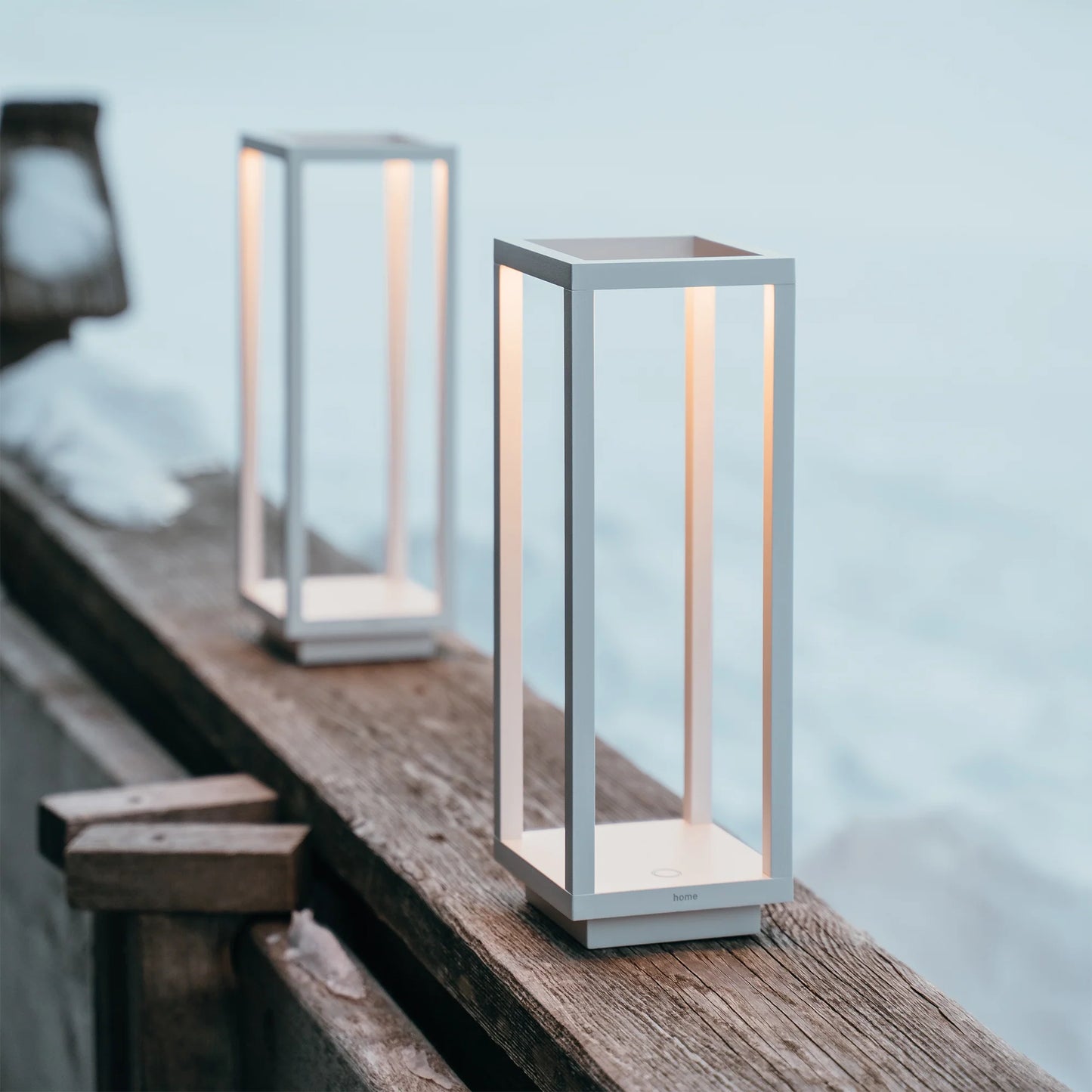 Two modern outdoor lamps on a wooden surface with a blurred natural background