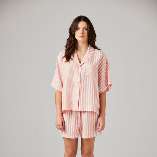 Woman wearing a pink striped linen pyjamas on a white background