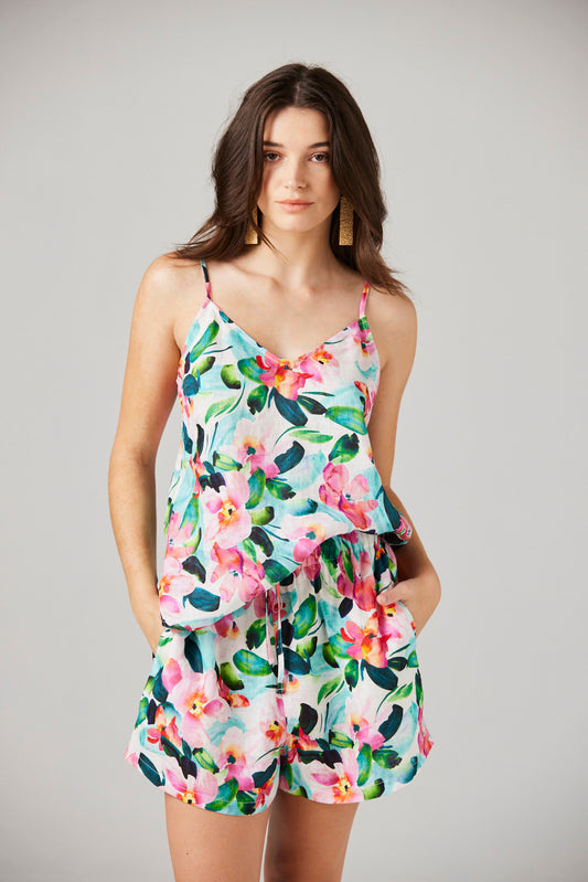 Woman wearing a floral line shorts and cami against a plain background