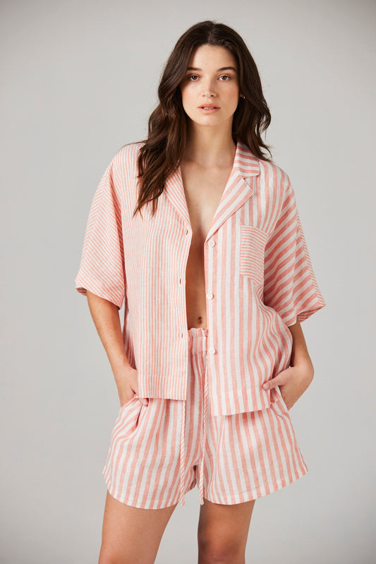 Woman wearing a pink striped pajama set against a gray background