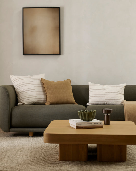 Modern living room with a gray sofa, wooden coffee table, and abstract art on the wall.