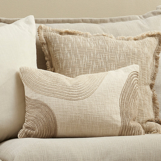 Textured pillows on a beige sofa against a neutral wall