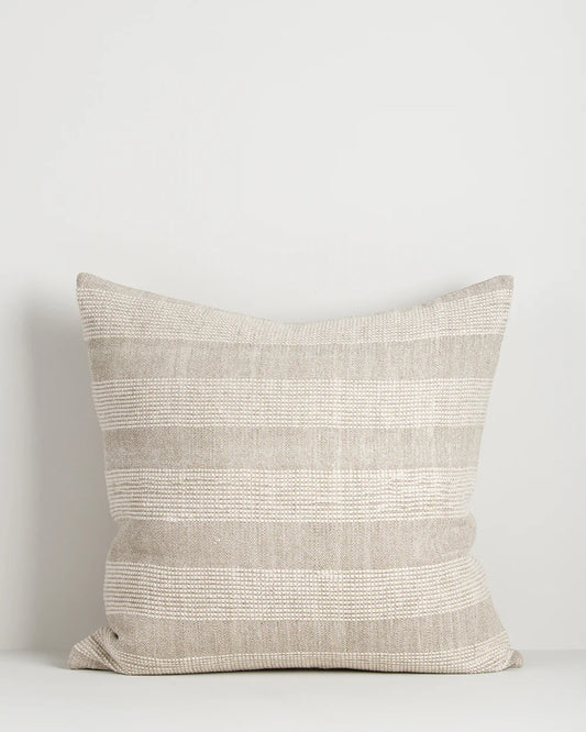 Textured pillow with a neutral color palette on a light gray background