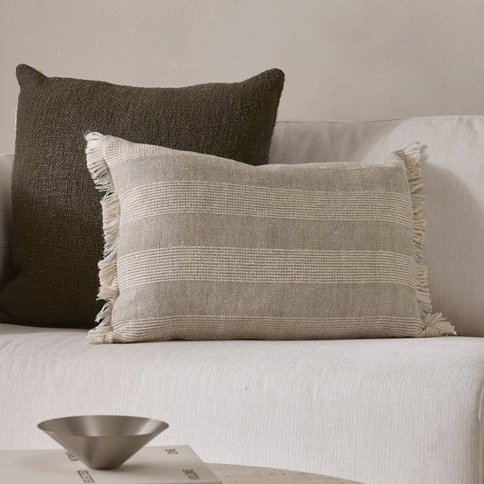 Two pillows on a sofa with a neutral color scheme.