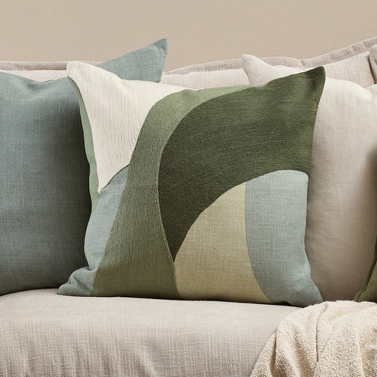 Decorative pillows in greens and blues on a sofa with a focus on color and design. Mid century style
