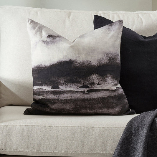 Decorative pillow with black and white abstract design on a light gray sofa.