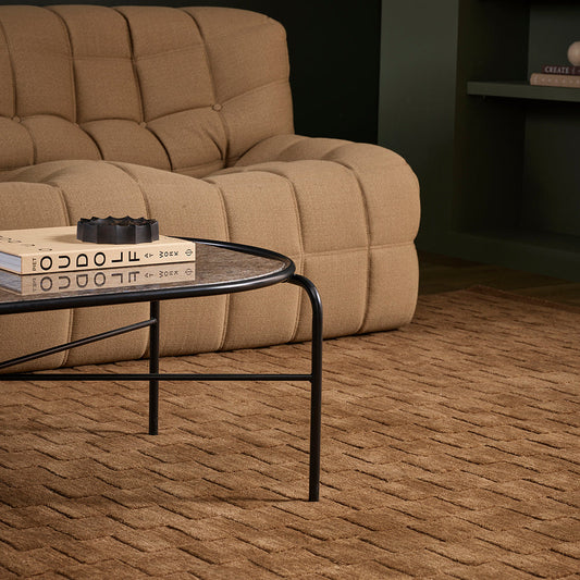 Beige recliner sofa in a living room with a coffee table and books.