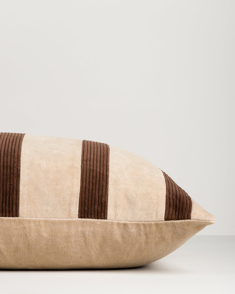 Beige pillow with brown stripes on a light gray background