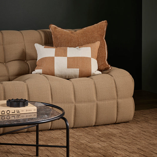 Beige sofa with decorative pillows in a dark room