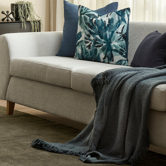 Gray sofa with decorative pillows and a blanket in a living room setting