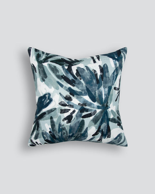 Decorative pillow with blue and green leaf pattern on a light gray background