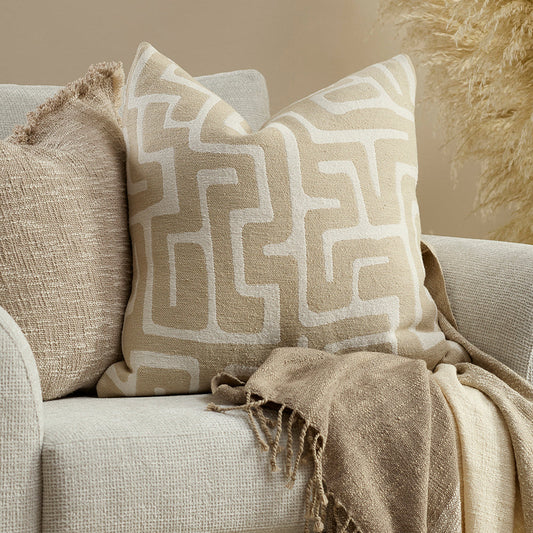 ivory and beige geometric pattern cushion on a cream sofa with another beige cushion