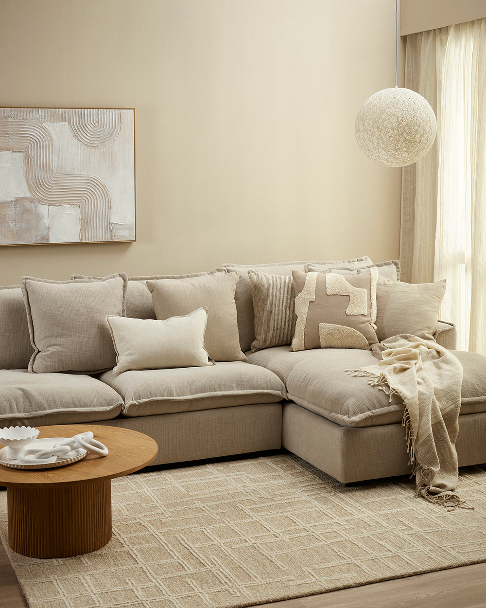 Beige sectional sofa in a living room with a coffee table and decorative items.