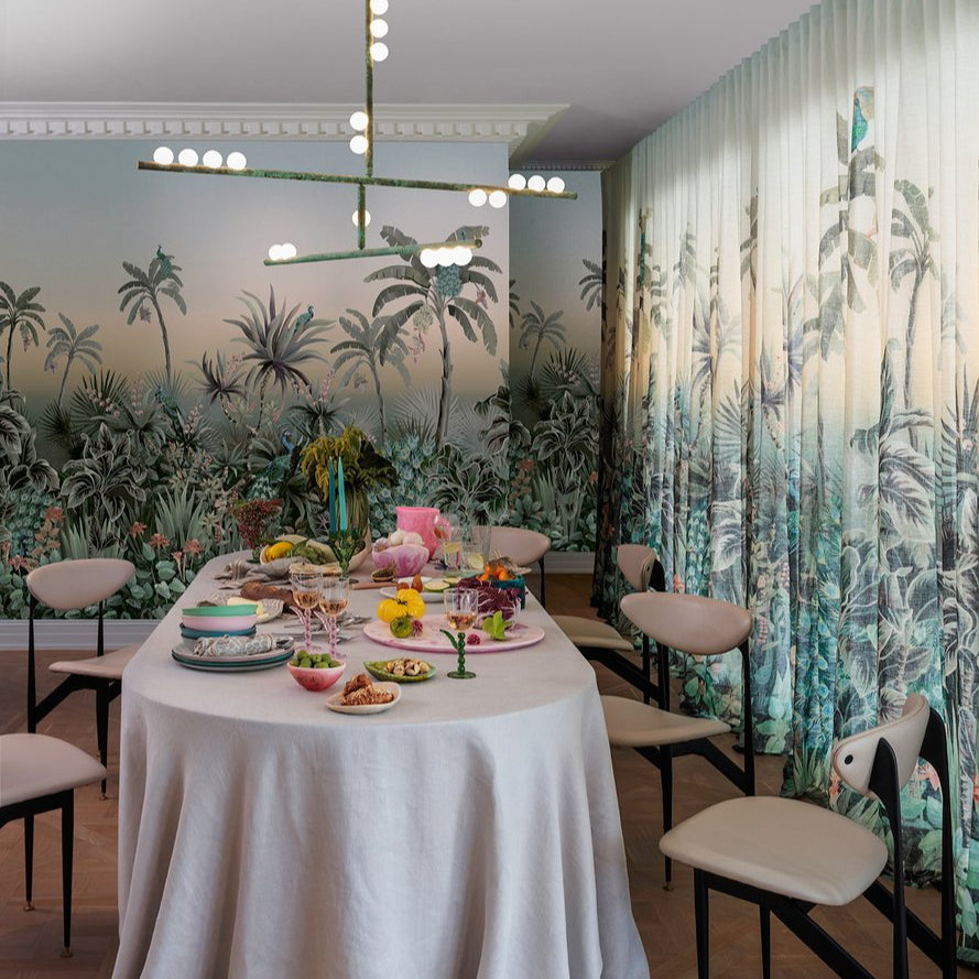 Dining room with a table set for a meal against a tropical-themed wall.