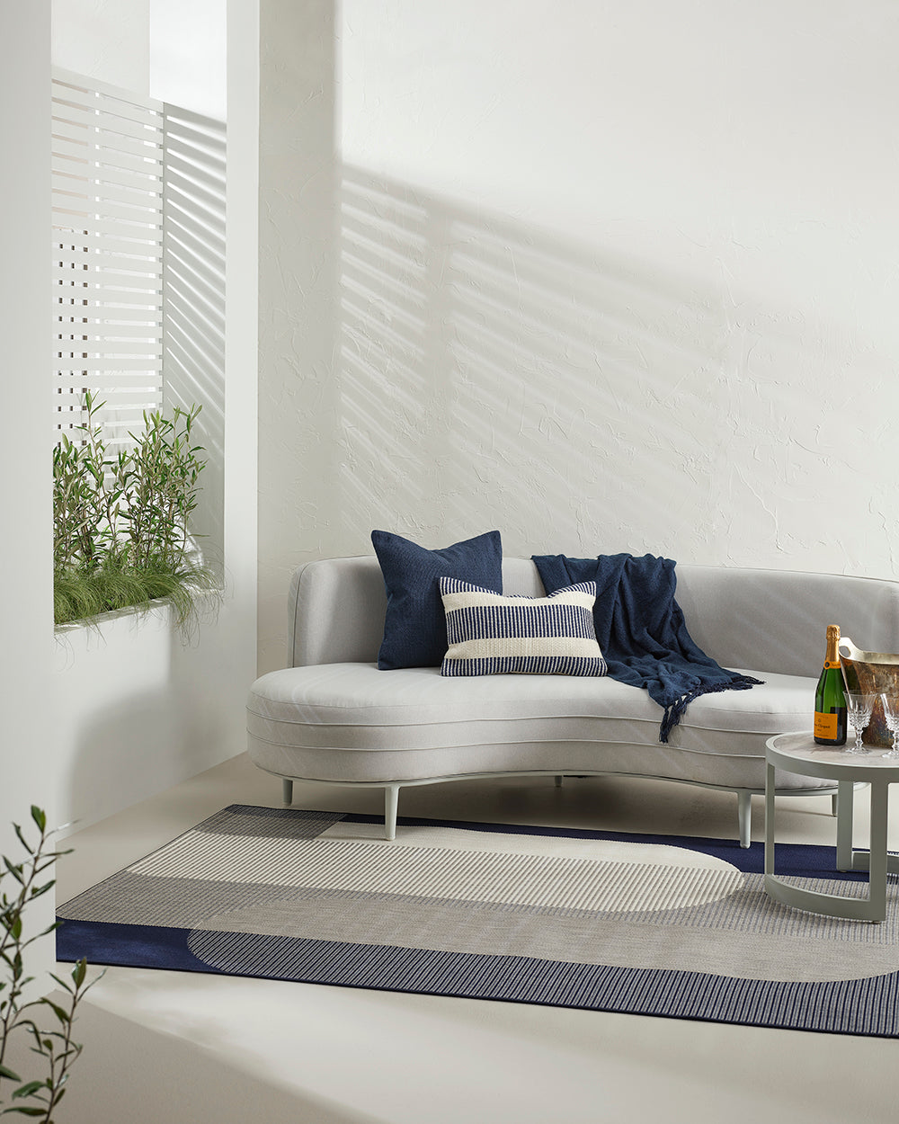 Modern outdoor seating area with a curved sofa, cushions, and a small table.