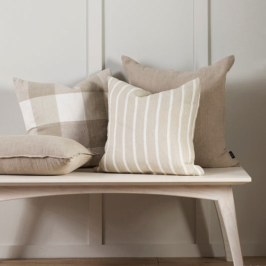 Oscar cushion and milano cushions sitting on a pale wood bench against a wooden paneled wall