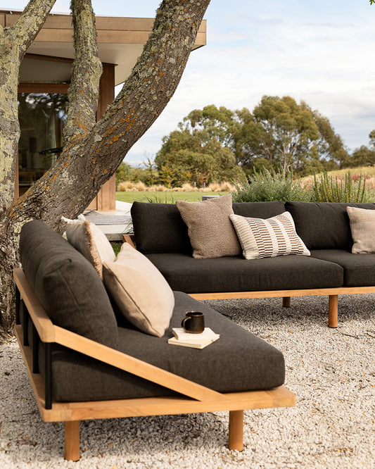 Outdoor sofa with cushions under a tree in a natural setting