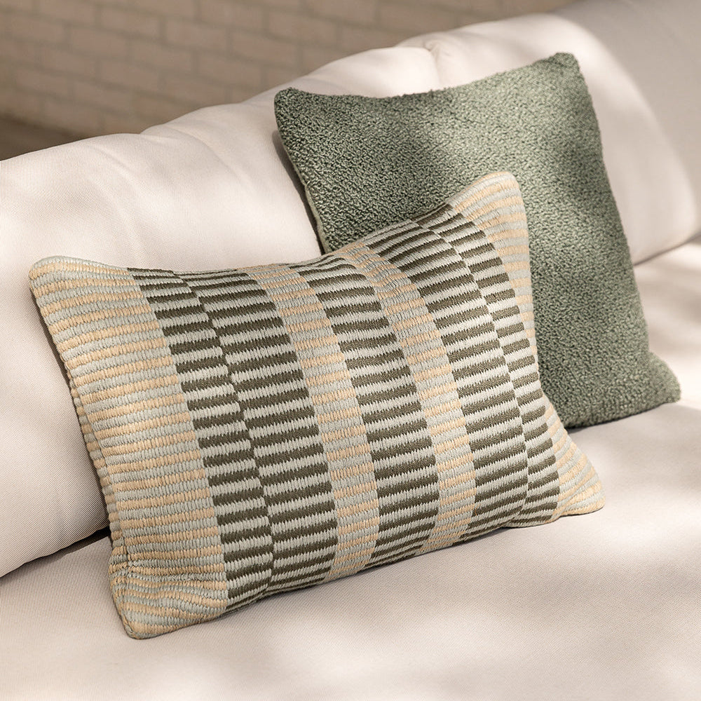 Two patterned pillows on a light-colored sofa with a neutral background