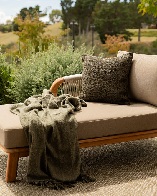Outdoor sofa with a blanket and pillow in a garden setting