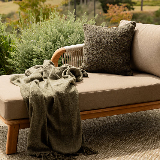 Outdoor sofa with a blanket and pillow in a garden setting