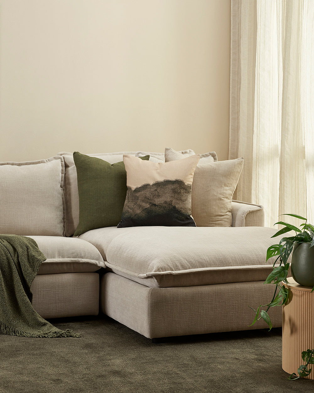Beige sectional sofa with decorative pillows in a living room setting.
