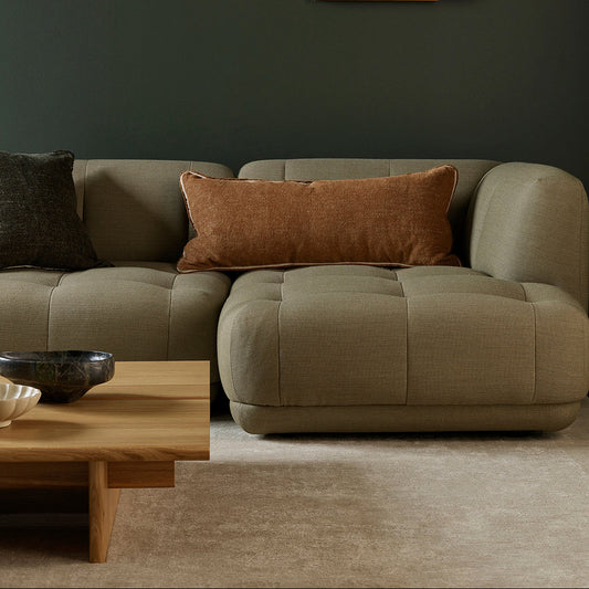 Modern living room with a beige sectional sofa, wooden coffee table, and abstract wall art.