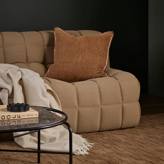 Beige sofa with a brown pillow in a darkly decorated room