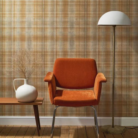 Orange armchair with a white vase and floor lamp against a plaid wall.