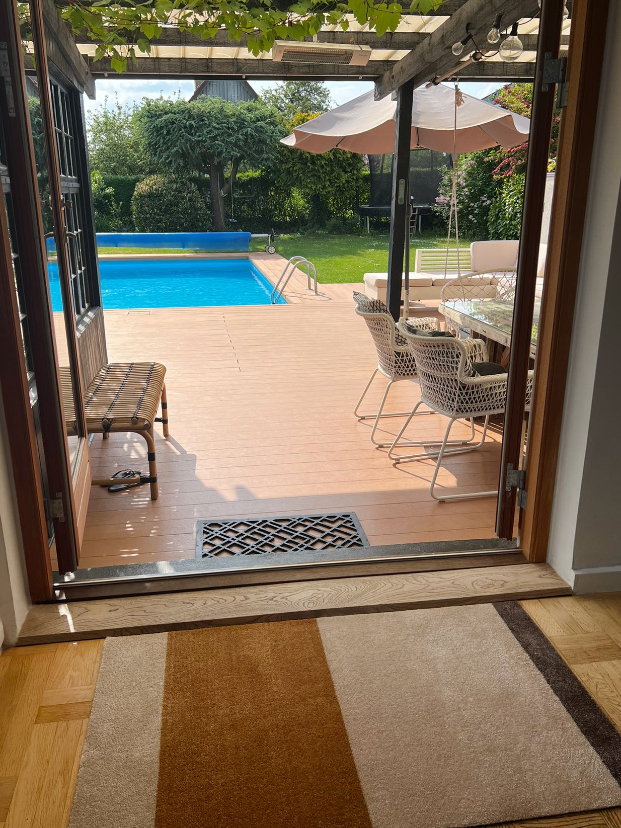 Open sliding glass door leading to a patio with a pool and outdoor furniture.