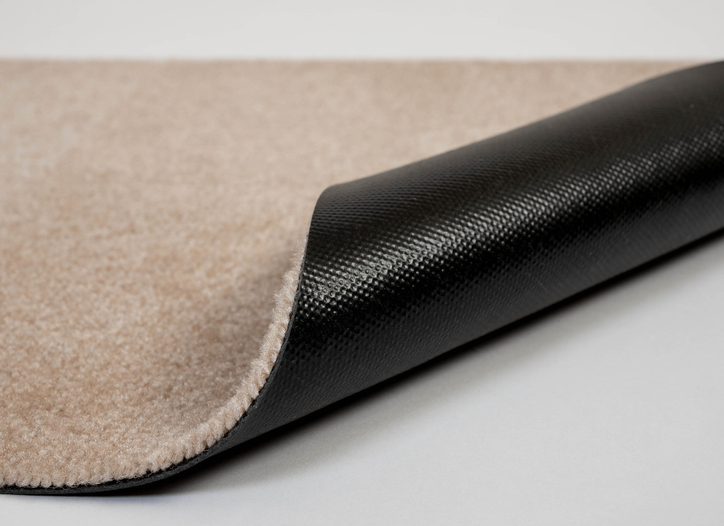 Close-up of a black and beige rug corner on a light gray background