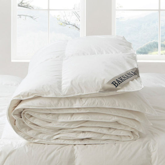 Hungarian Goose down and feather duvet inner folded on a bed with a window behind showing countryside