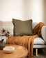 Maximum felt khaki cushion on a grey sofa with a rust coloured throw and textured beige cushion alongside