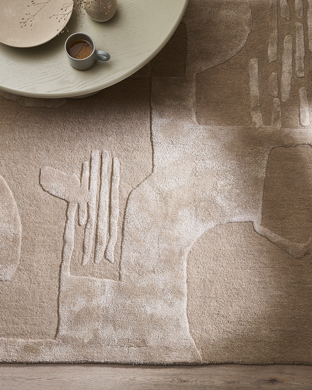 Paolo rug - pale cream with a wooden side table with a cup of coffee