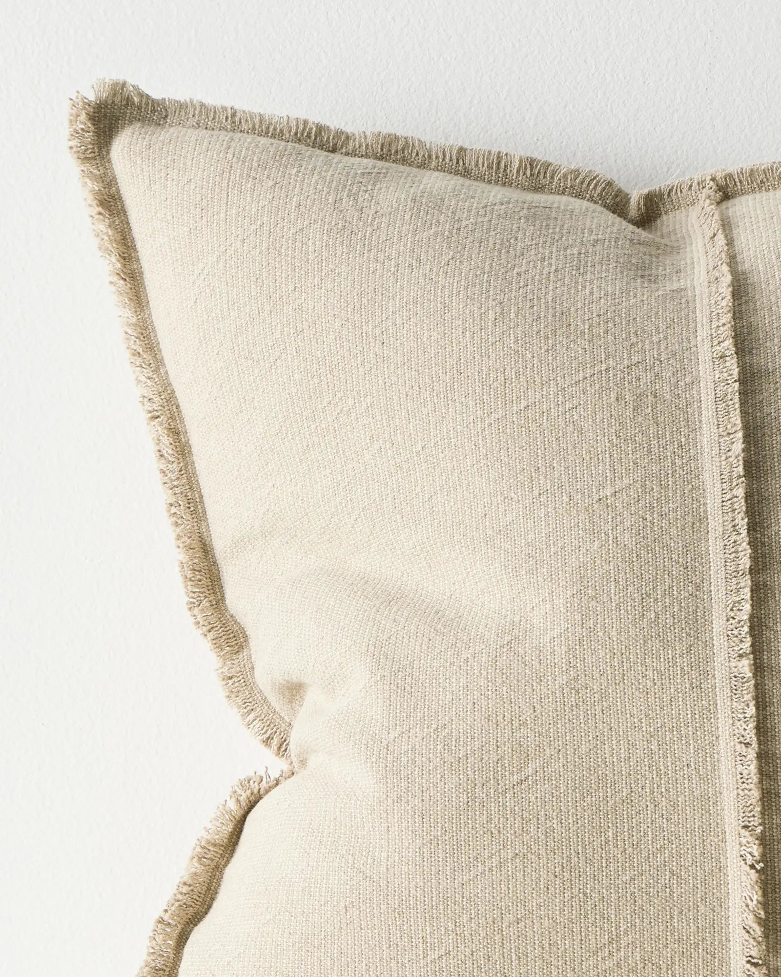 Beige pillow with frayed edges on a light background