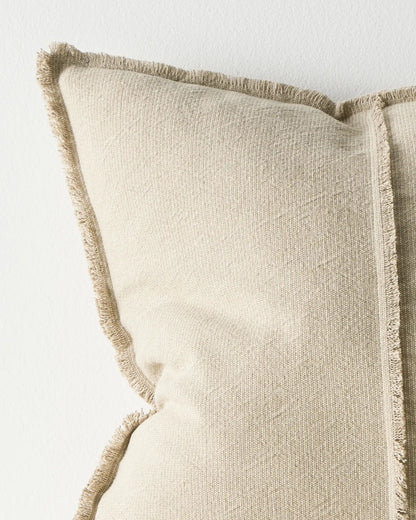 Beige pillow with frayed edges on a light background