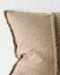 Close-up of a textured beige pillow with frayed edges on a light background