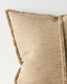 Beige pillow with textured fabric and frayed edges on a light background